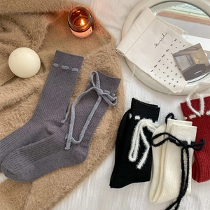 Nahaufnahme der gerippten Wollsocken mit Plüschschleifen-Details in warmen Farben