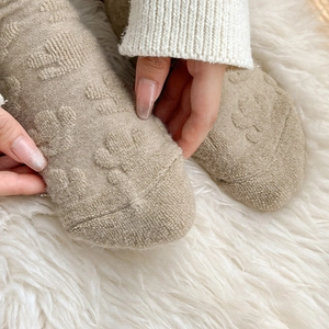 Detailed close-up of thick oatmeal wool socks with textured paw patterns and soft knit