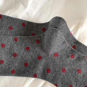 Detailed macro view of dark grey knit socks with burgundy polka dots and ribbed texture