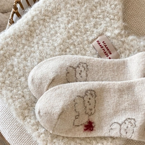 Close-up of soft beige knit wool socks featuring cute bear patterns and fuzzy texture