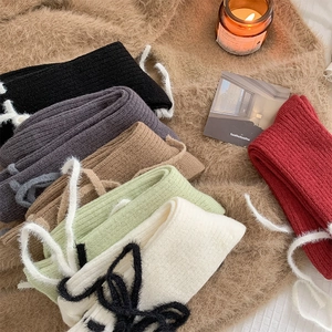 Detailansicht von gerippten Stricksocken mit Plüschschleifen in verschiedenen Farben
