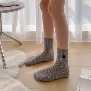 Detail view of grey ribbed cashmere crew socks featuring colorful decorative buttons