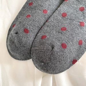 Macro shot of dark grey knit socks with red polka dots and reinforced toe stitching detail