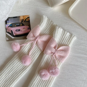 Détail de jambières Lolita en tricot blanc avec nœuds roses et pompons doux