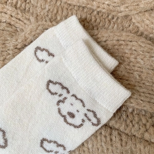 Dettaglio del motivo a cucciolo su calze di lana color crema con polsini a costine