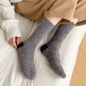Detail of gray wool socks featuring textured jacquard patterns and brown contrast heel