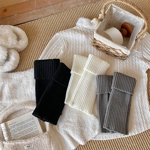Close-up of knit leg warmers in black, white and grey with vertical ribbed texture