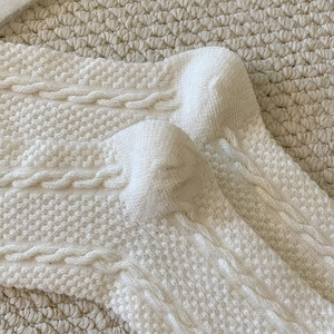 Macro detail of creamy white cable knit texture on thick winter wool crew socks