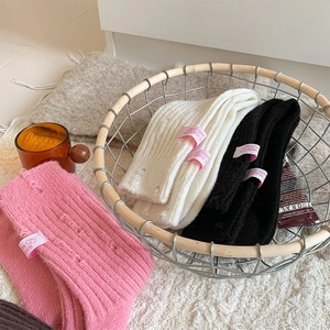 Detail of distressed knit cashmere socks with heart label in a rustic metal basket