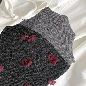 Close-up of charcoal grey knit socks with red 3D fuzzy dots and ribbed cuffs