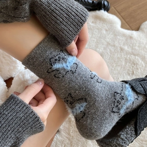 Detail of warm grey wool socks featuring a blue fuzzy cartoon cat pattern for winter
