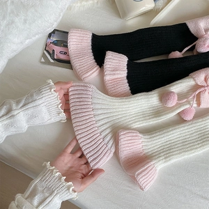 Détail de jambières Lolita avec rubans, pompons et bords festonnés