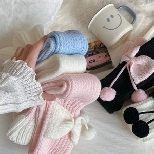 Détail de jambières en tricot avec nœuds et pompons sur une surface en peluche douce