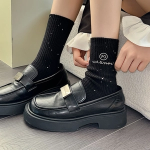 Close-up of black wool socks with silver sequins and embroidered logo detail