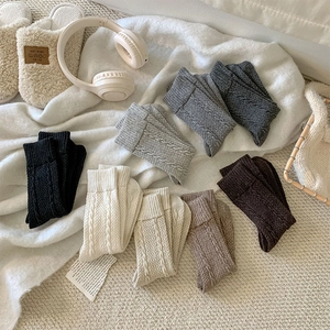 Close-up of thick cable-knit wool socks in six neutral colors for winter warmth