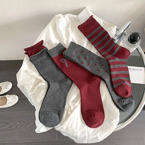 Detail showing vintage burgundy bow socks with stripes, dots, and ruffled edges texture