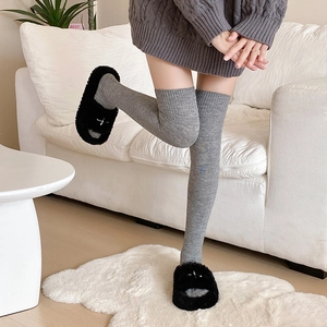 Gros plan de chaussettes hautes grises en maille et pantoufles en peluche noire douce