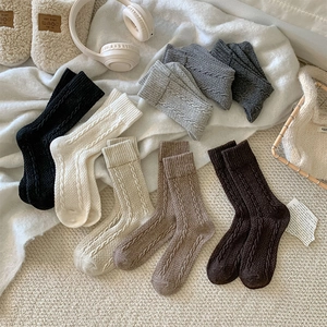 Detail view of thick cable knit wool crew socks in neutral tones for winter boots