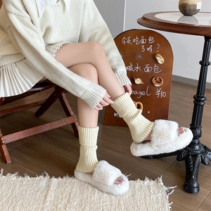 Detailed close-up of cream ribbed knit leg warmers and white faux fur slippers