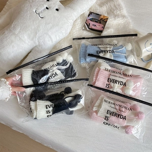 Détail de jambières en tricot style Lolita avec pompons dans des sacs individuels