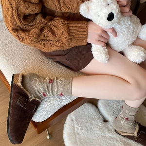 Detail of brown suede mule shoes with plush lining and decorative knit socks