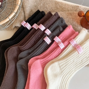 Close-up of thick knitted cashmere socks with 'made with love' label in various colors