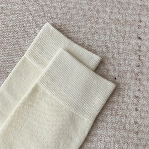 Gros plan d'une chaussette montante beige tricotée avec bord-côte fin et texture coton