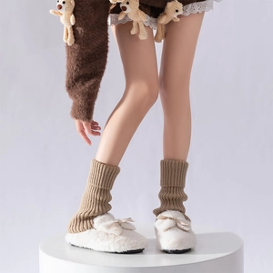 Detailed texture of khaki ribbed knit leg warmers paired with white plush bow slippers