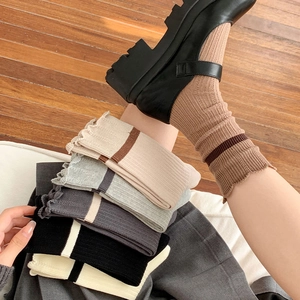 Detail of ruffled lace cuffs and striped textures on cotton blend mid-calf socks