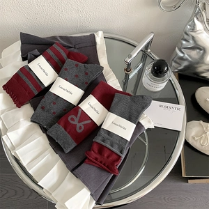 Close-up of vintage burgundy and grey mid-calf socks with patterns and bow details
