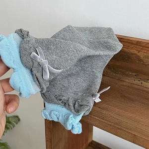 Detail of grey ribbed knit socks with light blue ruffle trim and velvet bow accent