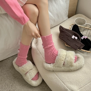 Close-up of pink cashmere knit socks with fabric label and fluffy beige plush slippers