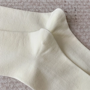Vue macro détaillée des chaussettes hautes crème montrant la texture fine du tricot