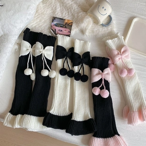 Détail de jambières en tricot avec nœuds et pompons doux sur fond en peluche blanche