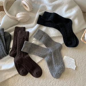 Detailed cable knit pattern on thick wool socks in black, coffee, and grey tones
