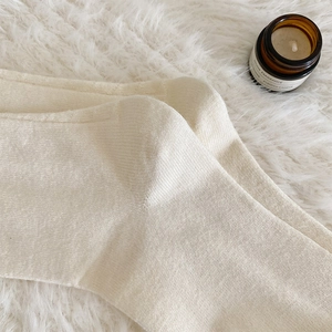Gros plan de chaussettes hautes en tricot crème avec une texture douce sur un tapis
