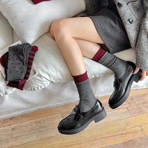 Detail of vintage burgundy bow socks paired with black patent leather platform loafers