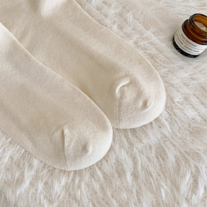 Gros plan de chaussettes hautes blanc cassé avec une texture douce et couture lisse