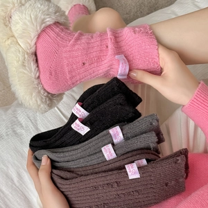 Detail of distressed cashmere socks with rib-knit texture and woven fashion labels