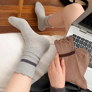 Close-up of ribbed knit socks with ruffled edges and contrast stripes in gray and brown