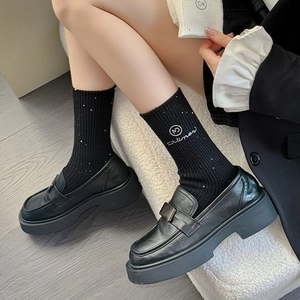 Thick wool socks with rhinestones and black platform loafers in a modern cozy setting