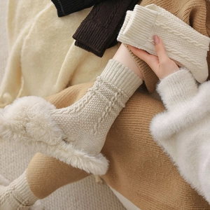 Detail of beige cable knit wool socks showing thick texture and warm braided pattern
