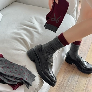 Detail of burgundy ribbed socks paired with black patent leather loafers in a vintage style