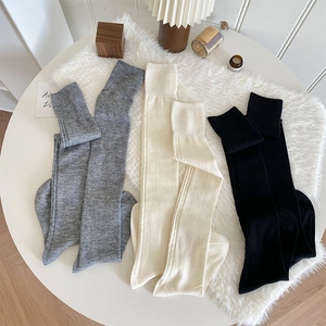 Texture tricotée détaillée des chaussettes montantes gris, blanc et noir sur fausse fourrure