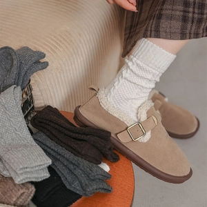 Close-up of khaki suede Birkenstock-style mules paired with cream cable-knit wool socks