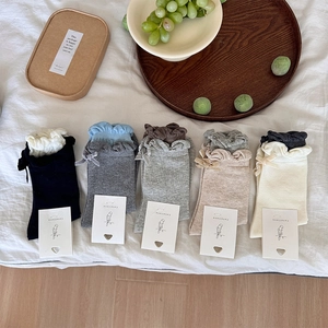 Detail of five-color knit cotton socks featuring delicate bow ties and ruffled edges