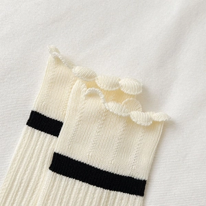 Close-up of ribbed cotton crew socks with black stripes and ruffled lettuce edge trim