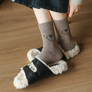 Détail de chaussettes en laine à motif d'ours avec des pantoufles confortables