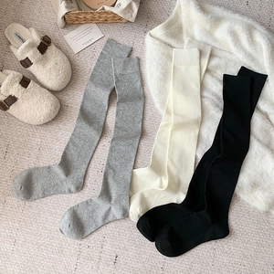 Texture détaillée de chaussettes hautes grises, crème et noires en tricot côtelé