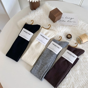 Détail de quatre paires de chaussettes hautes en tricot épais en noir, beige, gris et marron